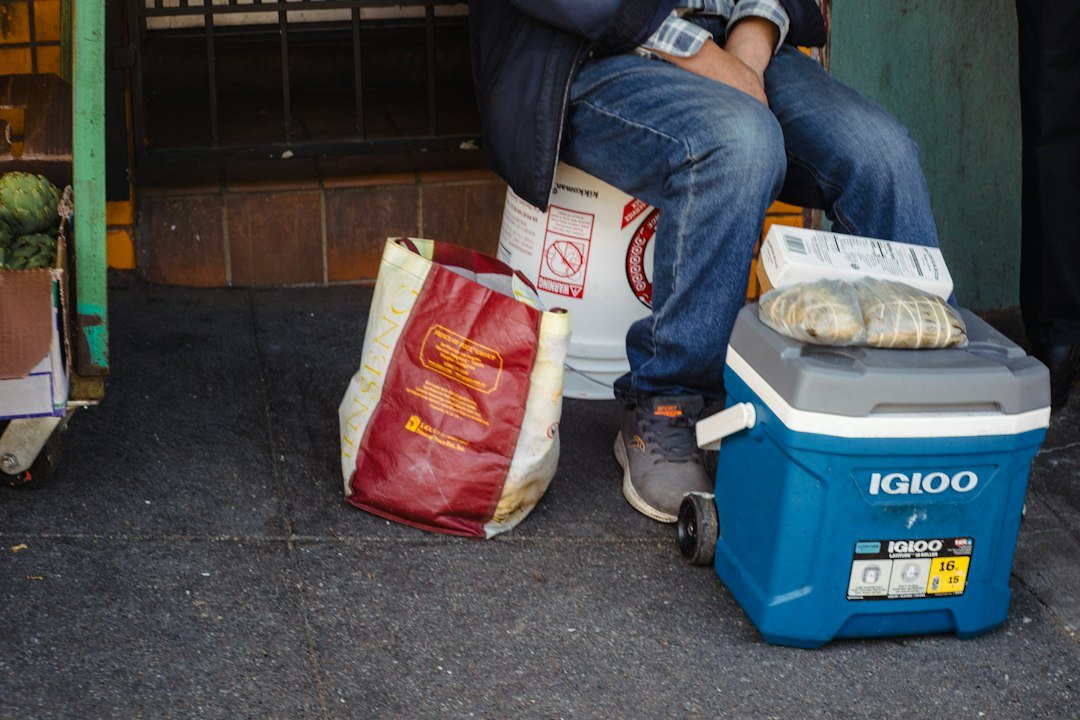 Person sits next to food and cooler outside