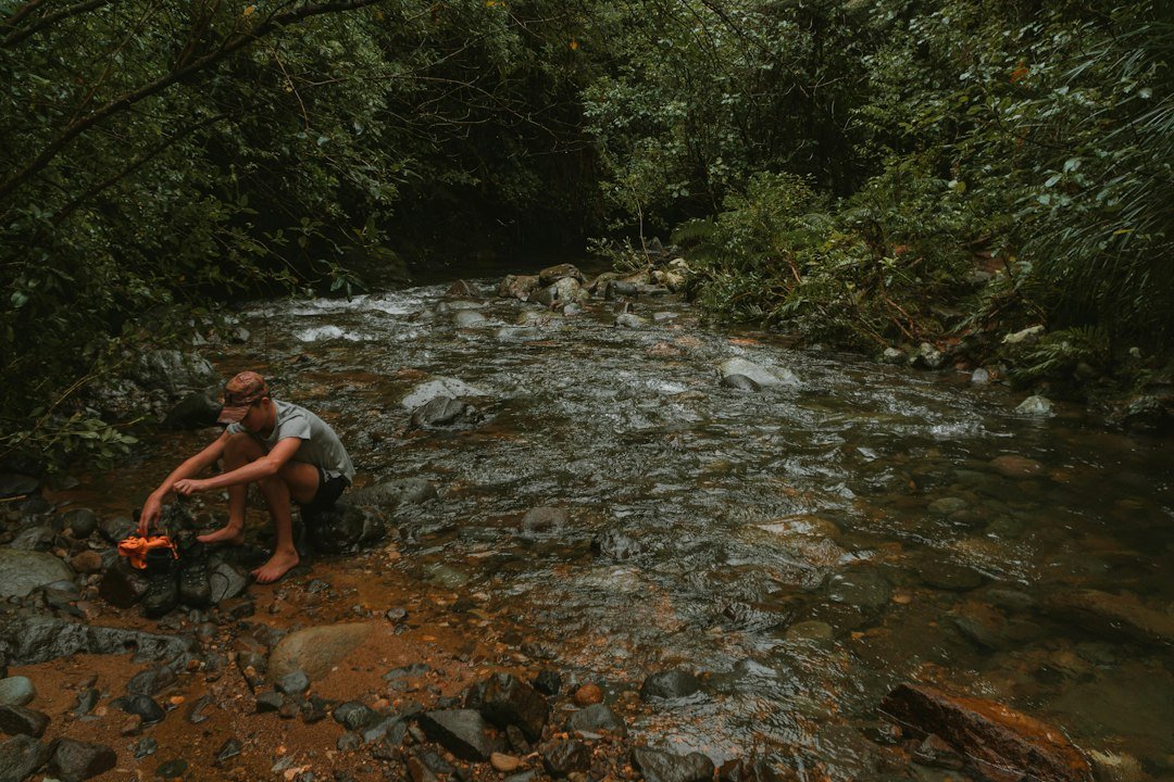 a man squatting in a creek
